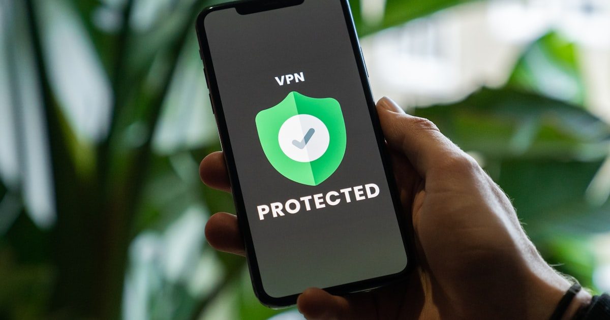 Hand holding smartphone with VPN service enabled on screen