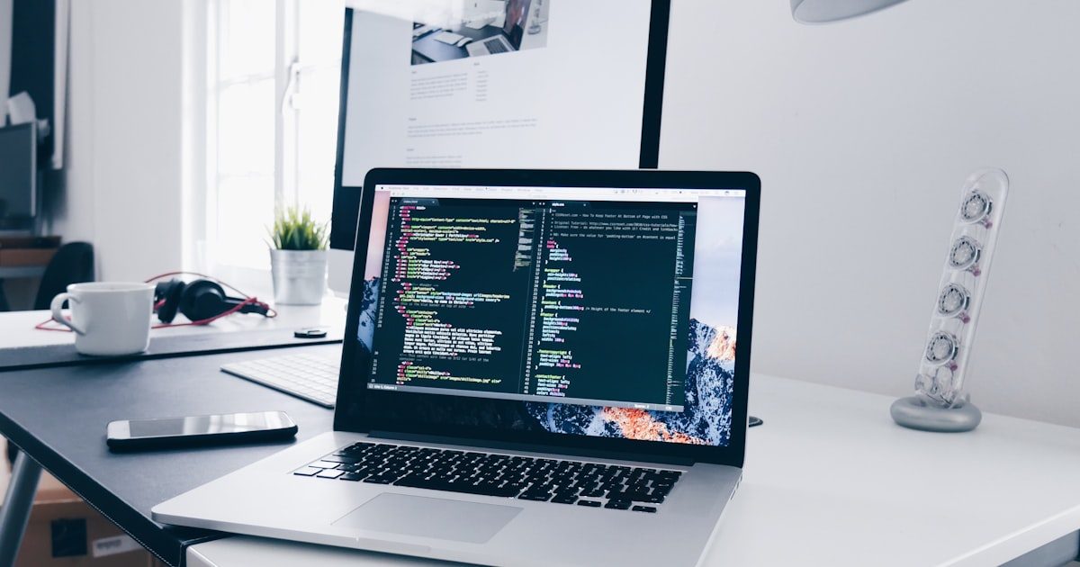 Developer working on code with laptop showing web application